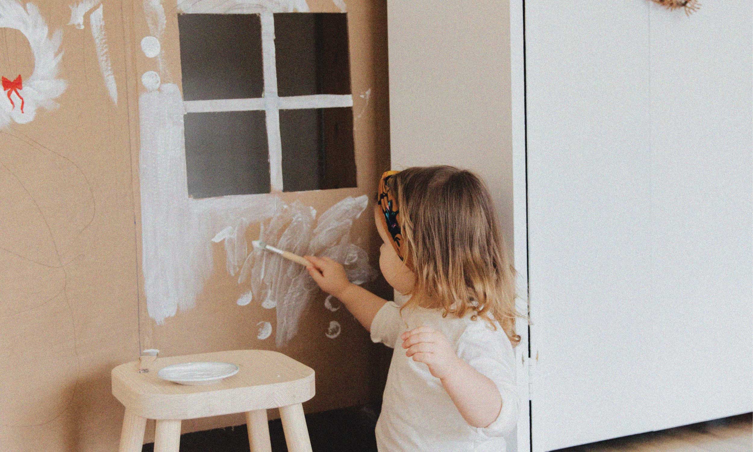 Child painting on cardboard, representing creativity, play and joyful energy.