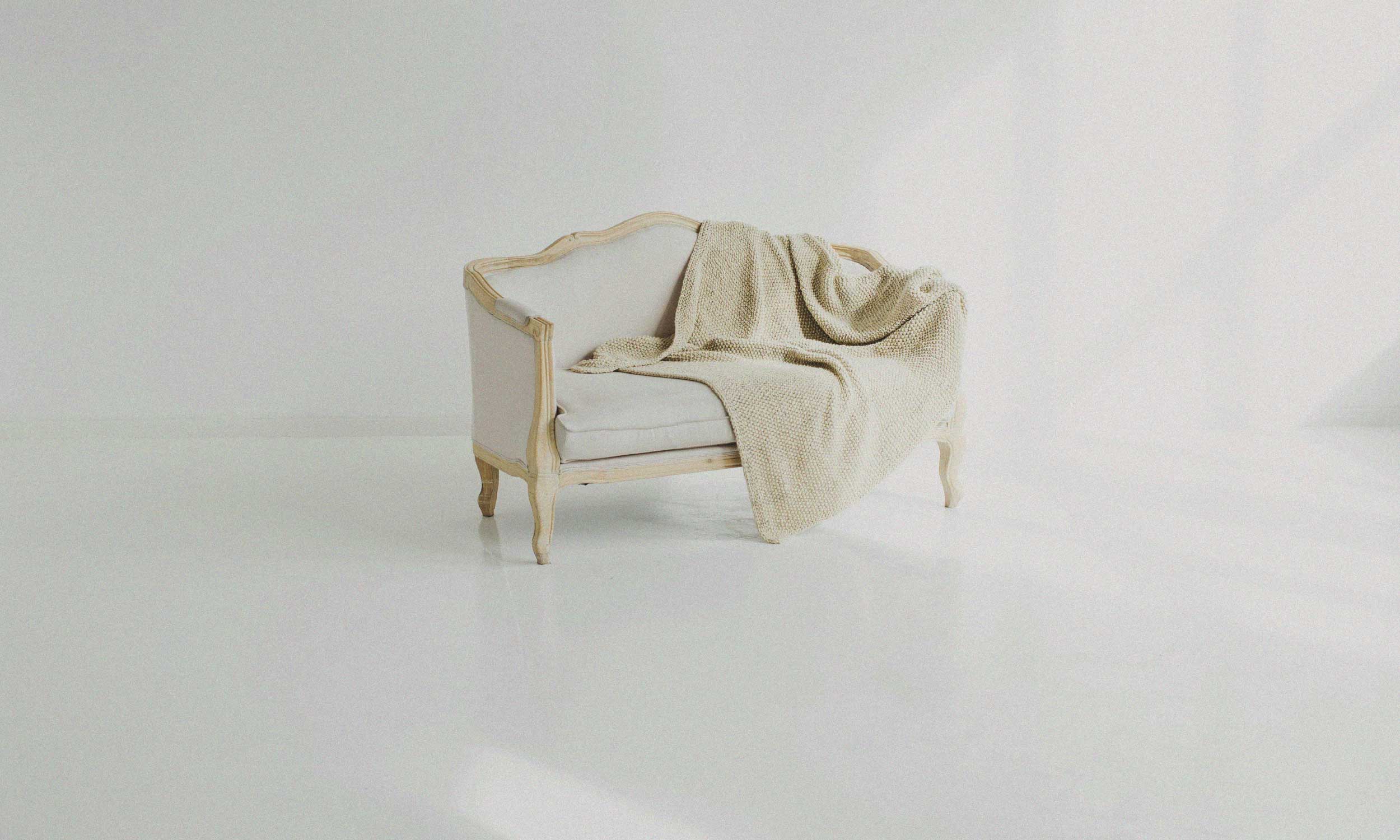 Minimal cream armchair with a soft blanket, representing comfort, simplicity and living lightly.