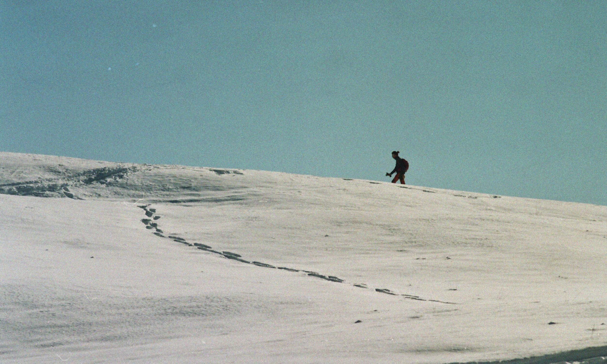 Person hiking across a snowy landscape, symbolising mental energy recovery, resilience and renewed focus.