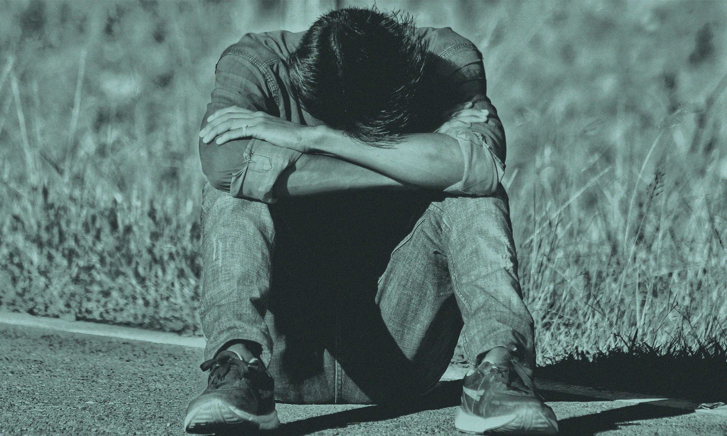 Man sitting with his head down, illustrating low energy caused by hormones, habits and hidden drains.