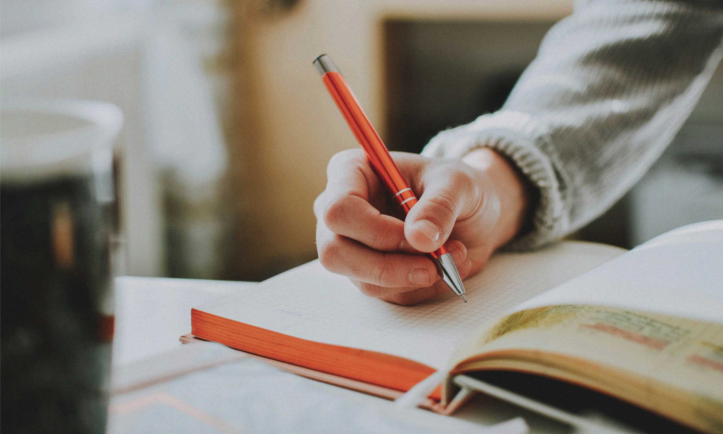 Person writing notes in a notebook, representing the habit of learning something small every day.