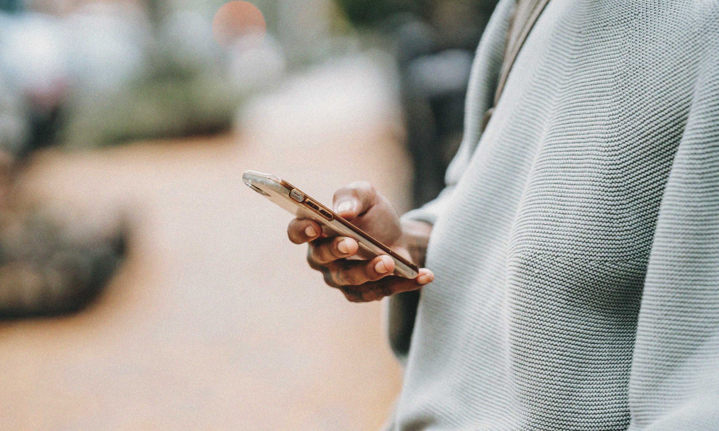 Person checking a smartphone, illustrating anxiety while waiting for a reply.