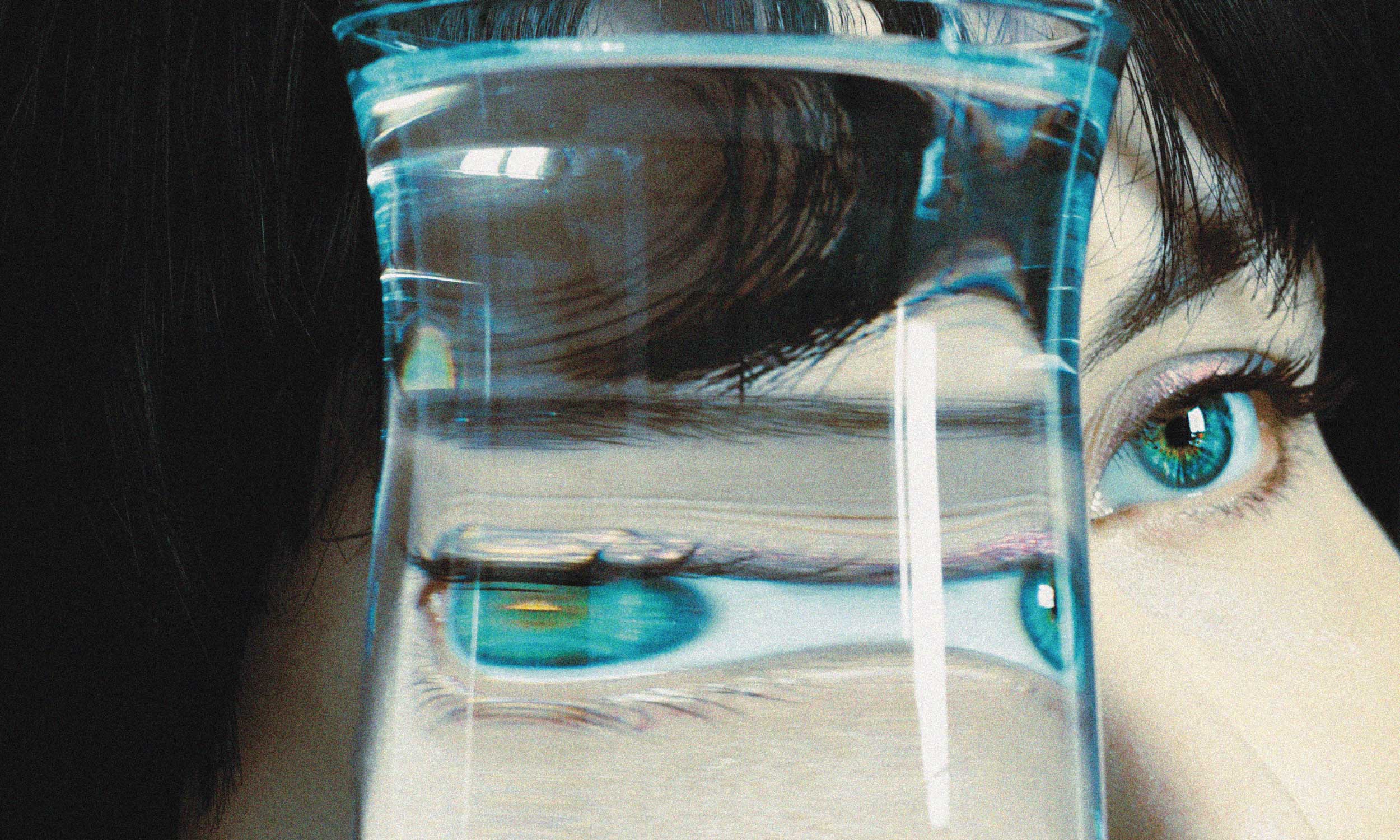 Close-up of a person’s eyes distorted through a glass of water, illustrating how distorted thinking shapes your behaviour
